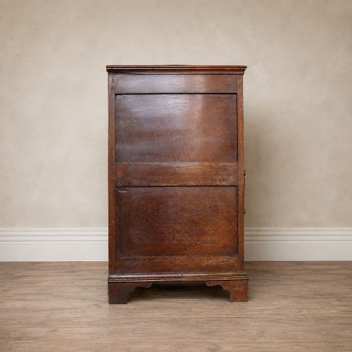 fig 4. An early eighteenth-century oak chest of drawers featuring four drawers decorated with geometric applied mouldings and brass drop handles.