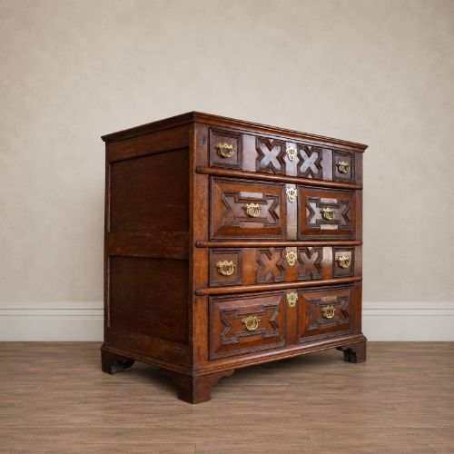 fig 5. An early eighteenth-century oak chest of drawers featuring four drawers decorated with geometric applied mouldings and brass drop handles.