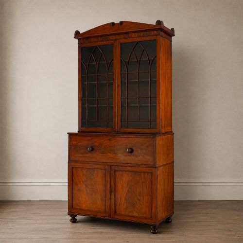 fig 5. A nineteenth-century George IV mahogany secretaire bookcase with glazed upper doors featuring gothic tracery and a drop-down desk drawer revealing a fitted interior.
