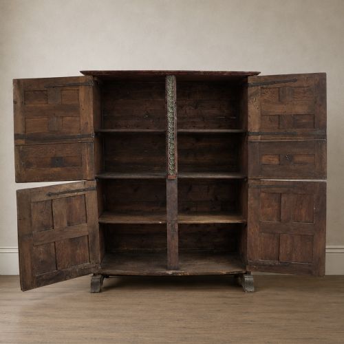 fig 1. A tall seventeenth-century Spanish oak press cupboard featuring double upper and lower doors decorated with geometric raised panels and painted polychrome geometric patterns.