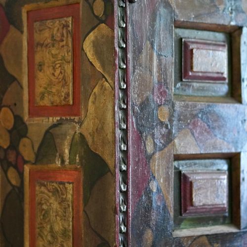 fig 3. A tall seventeenth-century Spanish oak press cupboard featuring double upper and lower doors decorated with geometric raised panels and painted polychrome geometric patterns.