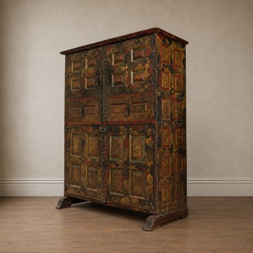 fig 6. A tall seventeenth-century Spanish oak press cupboard featuring double upper and lower doors decorated with geometric raised panels and painted polychrome geometric patterns.