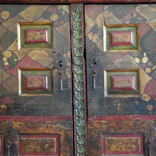 fig 7. A tall seventeenth-century Spanish oak press cupboard featuring double upper and lower doors decorated with geometric raised panels and painted polychrome geometric patterns.