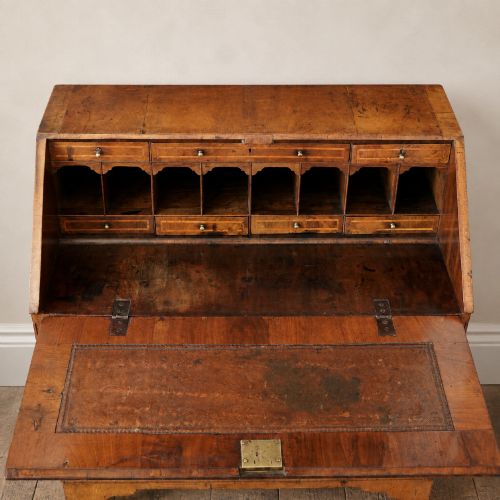 fig 8. An Early Georgian walnut bureau featuring a sloping drop-front writing lid, four graduated drawers with brass drop handles, and bracket feet.