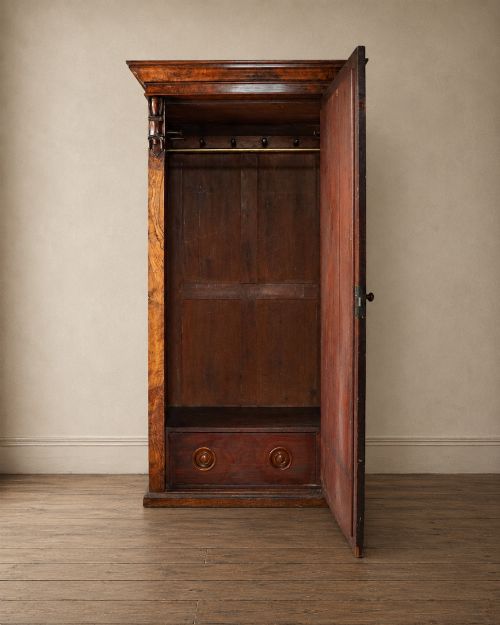fig 1. A Victorian single-door wardrobe crafted from figured walnut wood, featuring a central arch-topped mirror panel, carved corbels, and a heavy moulded cornice.
