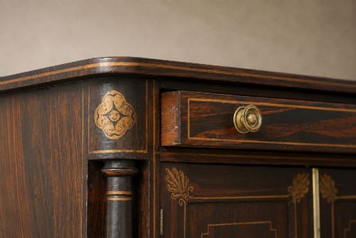 fig 7. A Regency period side cabinet featuring simulated rosewood graining, gilt corner decorations, turned flanking columns, a top drawer, and two cupboard doors.