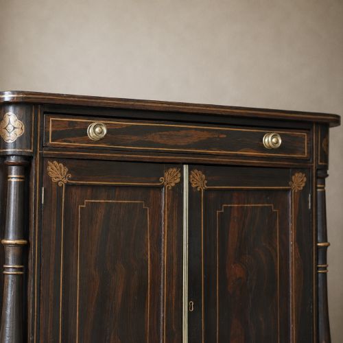 fig 8. A Regency period side cabinet featuring simulated rosewood graining, gilt corner decorations, turned flanking columns, a top drawer, and two cupboard doors.