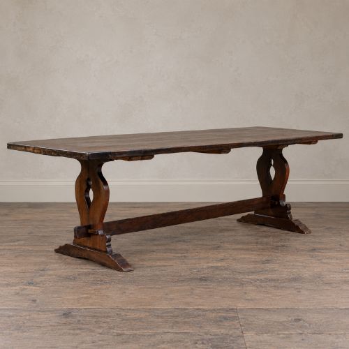 fig 2. An early twentieth-century dark oak refectory dining table featuring a plank top, pierced trestle end supports, and a central connecting stretcher.