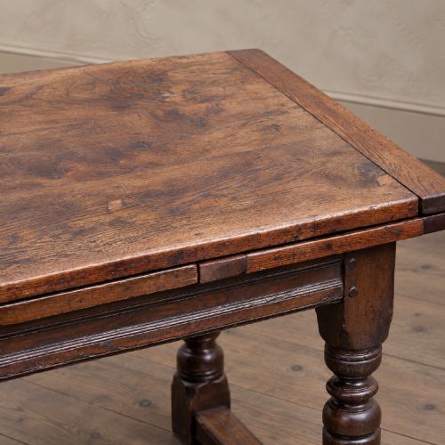 fig 5. A 17th-century solid oak extending dining table featuring turned legs, lower stretcher rails, and two draw-out end leaves.