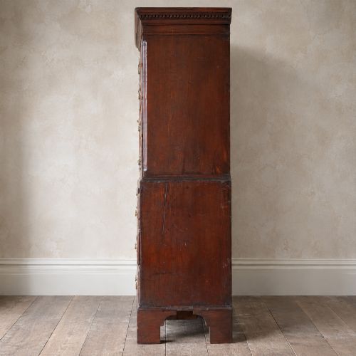 fig 2. An eighteenth-century Georgian figured mahogany chest on chest featuring a carved dentil cornice, brass swan-neck handles, a pull-out brushing slide, and bracket feet.