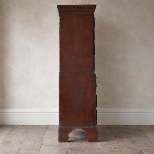 fig 4. An eighteenth-century Georgian figured mahogany chest on chest featuring a carved dentil cornice, brass swan-neck handles, a pull-out brushing slide, and bracket feet.