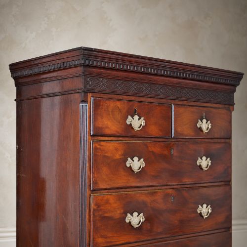 fig 6. An eighteenth-century Georgian figured mahogany chest on chest featuring a carved dentil cornice, brass swan-neck handles, a pull-out brushing slide, and bracket feet.