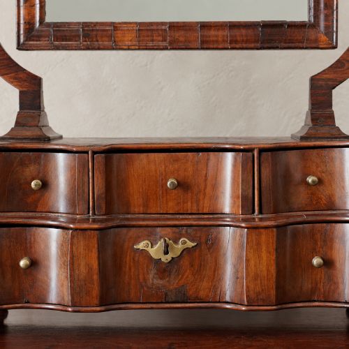 fig 6. An antique Queen Anne walnut and laburnum toilet mirror featuring an arched cross-banded frame above a serpentine base with miniature drawers.