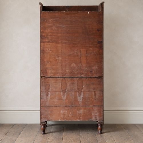 fig 4. A Regency period flame mahogany linen press featuring a two-door upper cupboard above four drawers resting on turned legs.