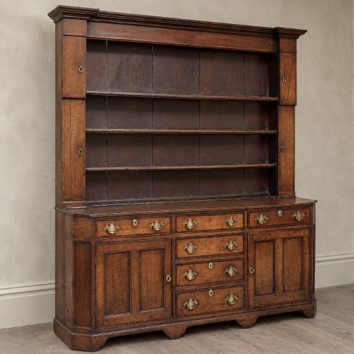 fig 4. A George II dark oak dresser with a tall open plate rack above a sideboard featuring multiple drawers and twin cupboard doors.