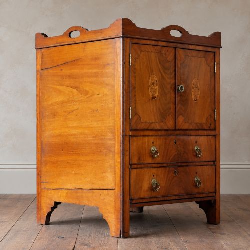 fig 3. A 19th-century mahogany tray top night commode featuring two cabinet doors with oval marquetry inlays above two drawers with brass handles.