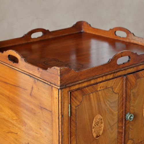 fig 7. A 19th-century mahogany tray top night commode featuring two cabinet doors with oval marquetry inlays above two drawers with brass handles.