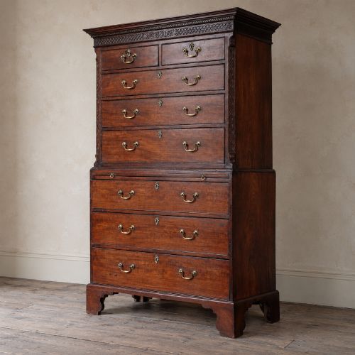 fig 2. A George III mahogany chest on chest featuring two short over six long graduated drawers, a brushing slide, blind fretwork frieze, brass swan-neck handles, and bracket feet.