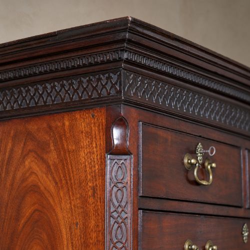 fig 4. A George III mahogany chest on chest featuring two short over six long graduated drawers, a brushing slide, blind fretwork frieze, brass swan-neck handles, and bracket feet.