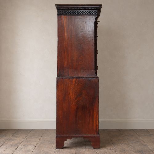 fig 6. A George III mahogany chest on chest featuring two short over six long graduated drawers, a brushing slide, blind fretwork frieze, brass swan-neck handles, and bracket feet.