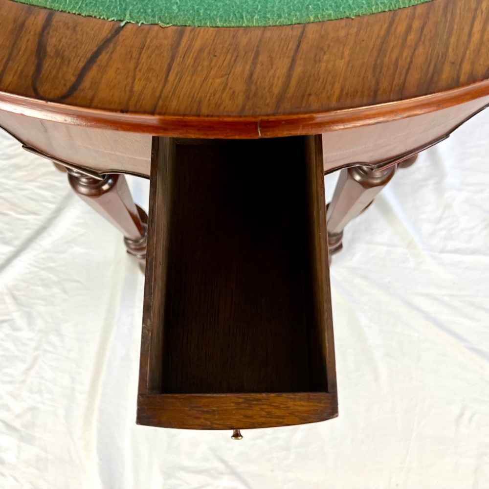 A Victorian figured walnut demi-lune card table featuring a scalloped apron, small frieze drawers, multiple turned legs, and a shaped stretcher base. View III