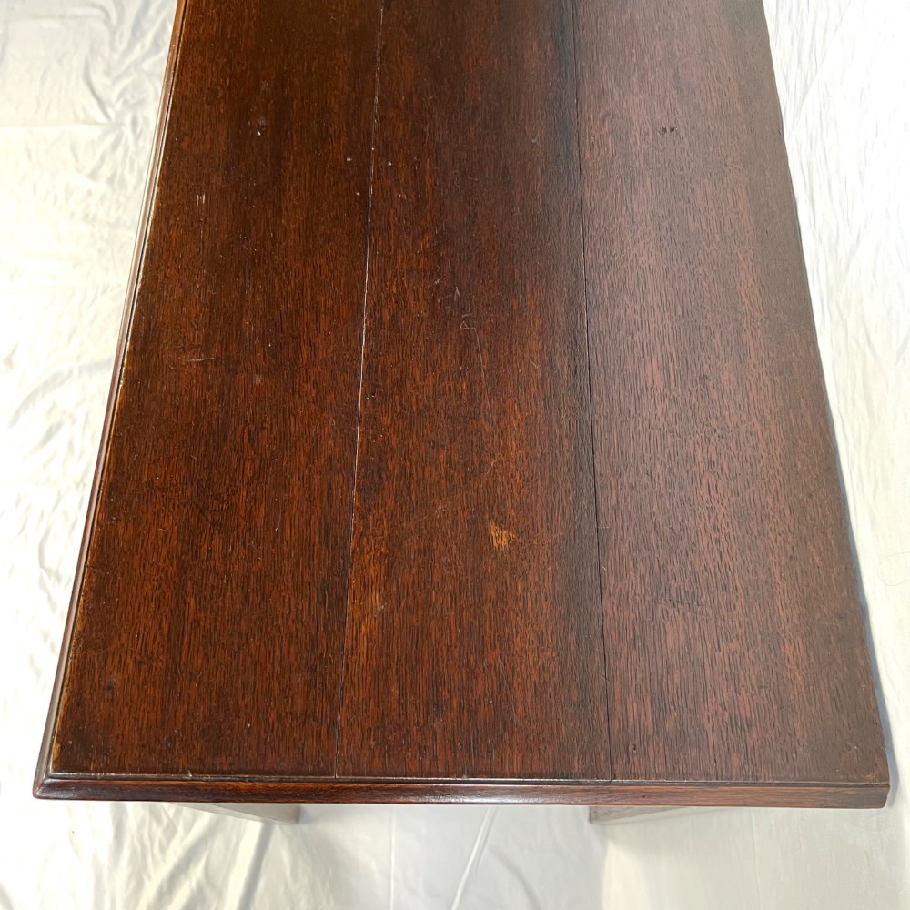 A George III dark oak lowboy table featuring three drawers with brass swan-neck handles, a shaped apron, and four square straight legs. View XII