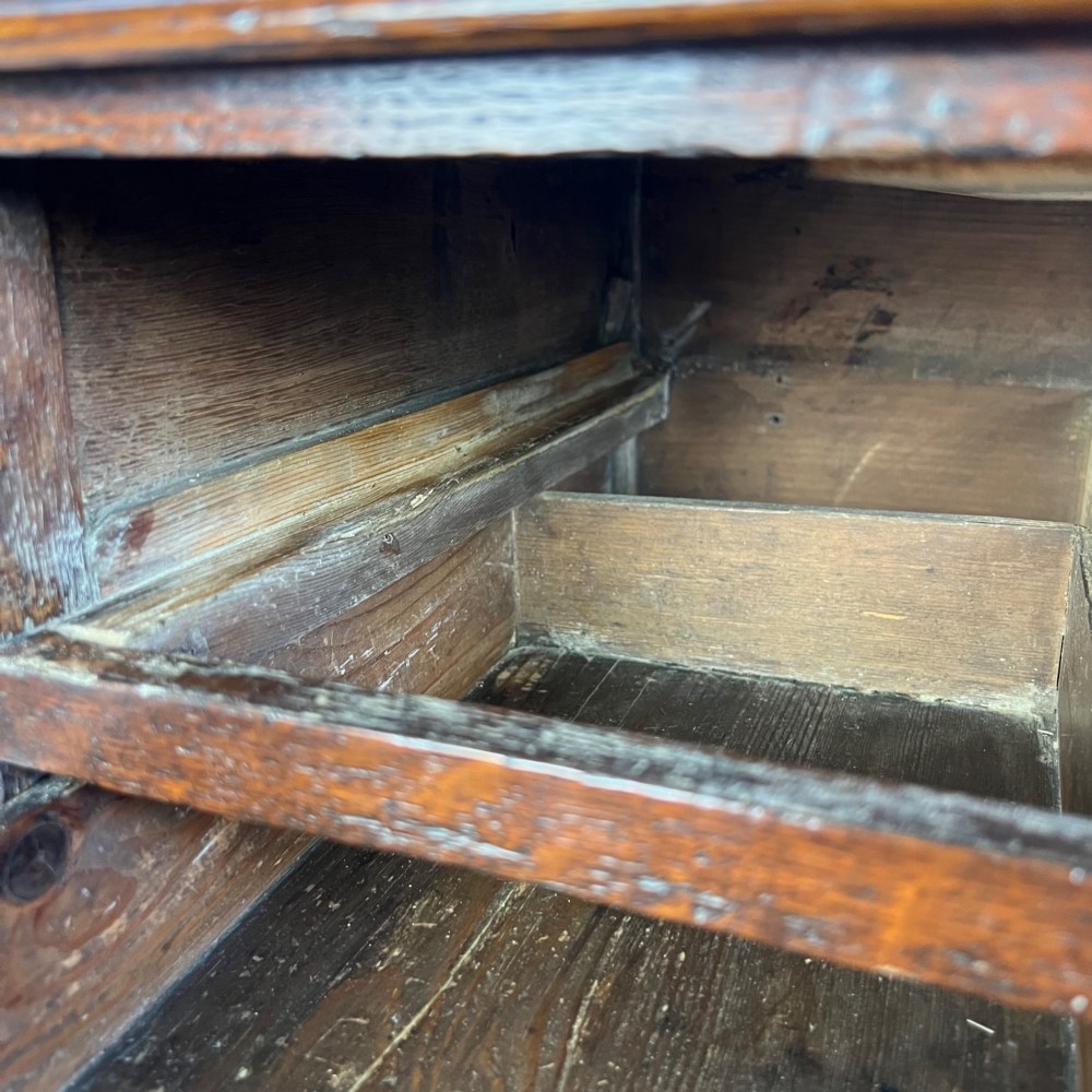 A George III dark oak lowboy table featuring three drawers with brass swan-neck handles, a shaped apron, and four square straight legs. View XV