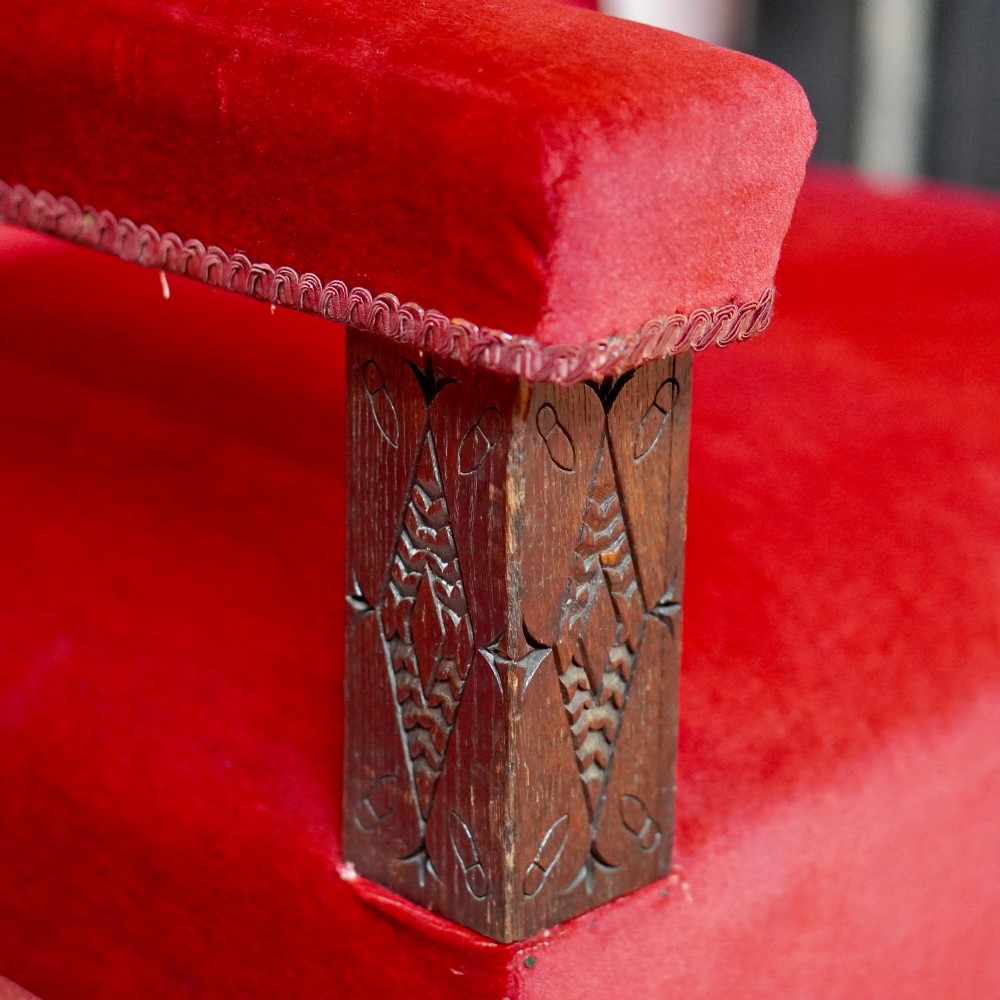 A pair of oversized Victorian armchairs upholstered in crimson red velvet with fringe trim, featuring carved oak arm supports and bobbin-turned legs. View V