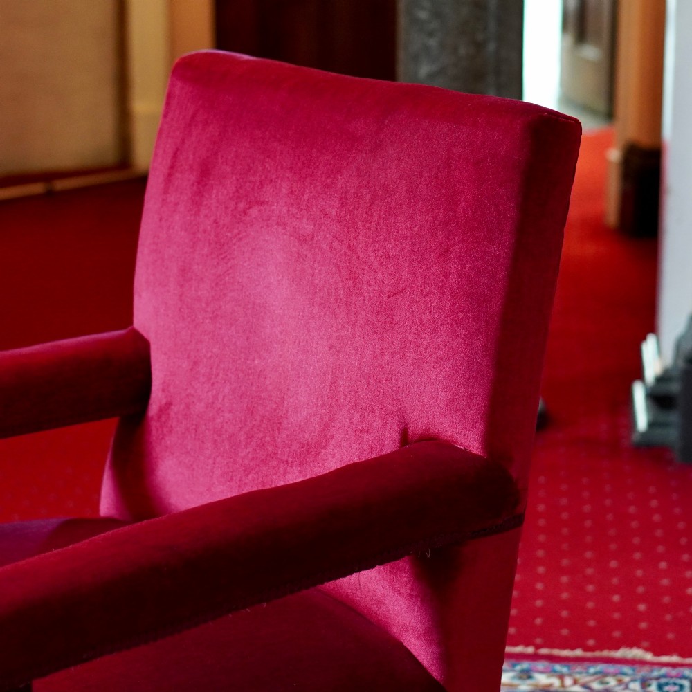 A pair of oversized Victorian armchairs upholstered in crimson red velvet with fringe trim, featuring carved oak arm supports and bobbin-turned legs. View XI