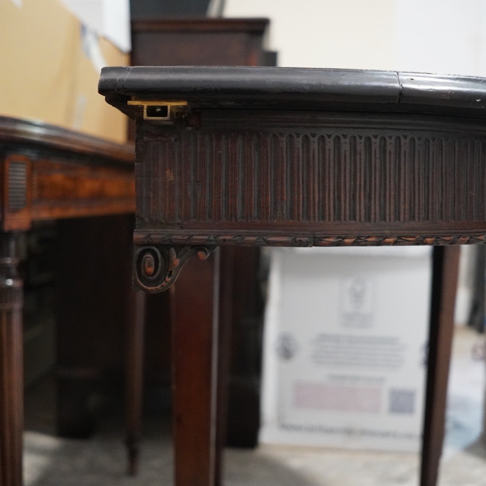 A long late George III mahogany extending dining table with D-shaped end sections, fluted friezes, carved paterae, and square tapered legs. View VII