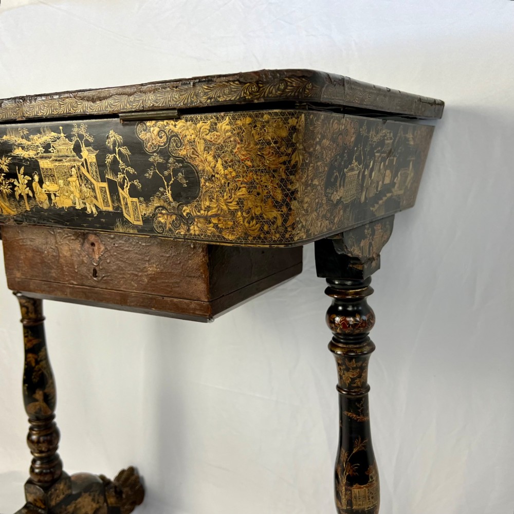 A Regency era black lacquered work table featuring detailed gold chinoiserie motifs, turned legs, a stretcher base, and carved paw feet. View X