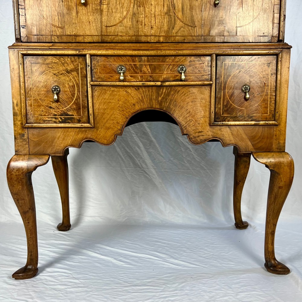 An early 18th-century Queen Anne walnut chest on stand featuring crossbanded drawers, brass teardrop handles, and cabriole legs. View III