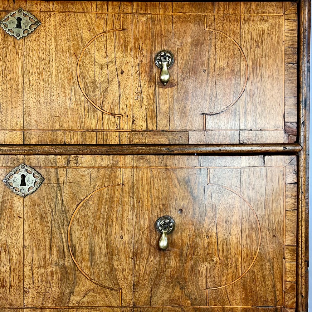 An early 18th-century Queen Anne walnut chest on stand featuring crossbanded drawers, brass teardrop handles, and cabriole legs. View IV