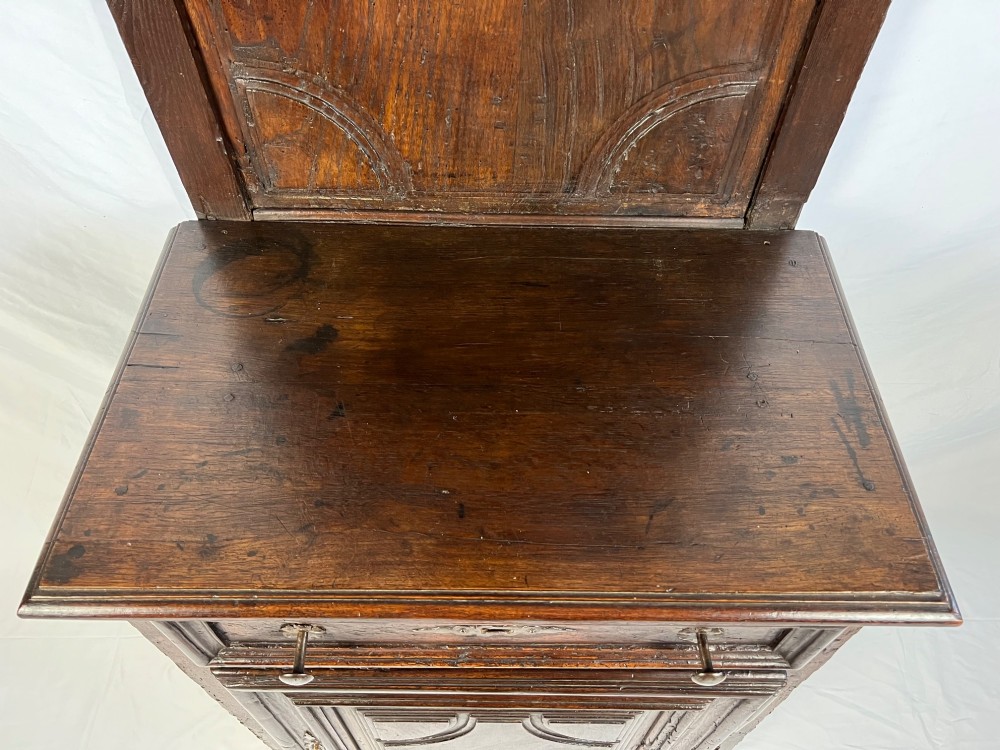 An 18th-century dark chestnut wood lavabo cabinet featuring a carved backboard mounted with a pewter cistern above a matching pewter basin. View II