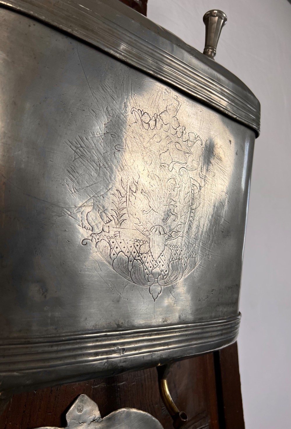 An 18th-century dark chestnut wood lavabo cabinet featuring a carved backboard mounted with a pewter cistern above a matching pewter basin. View VII