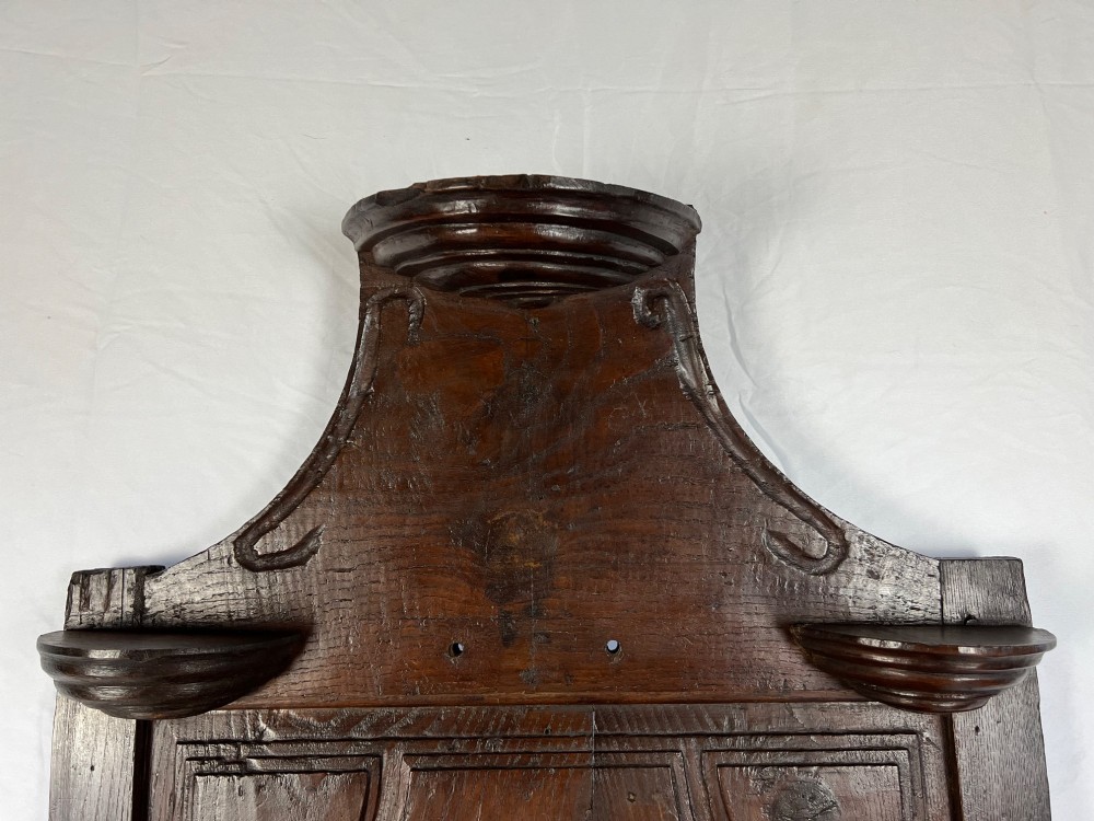 An 18th-century dark chestnut wood lavabo cabinet featuring a carved backboard mounted with a pewter cistern above a matching pewter basin. View IX