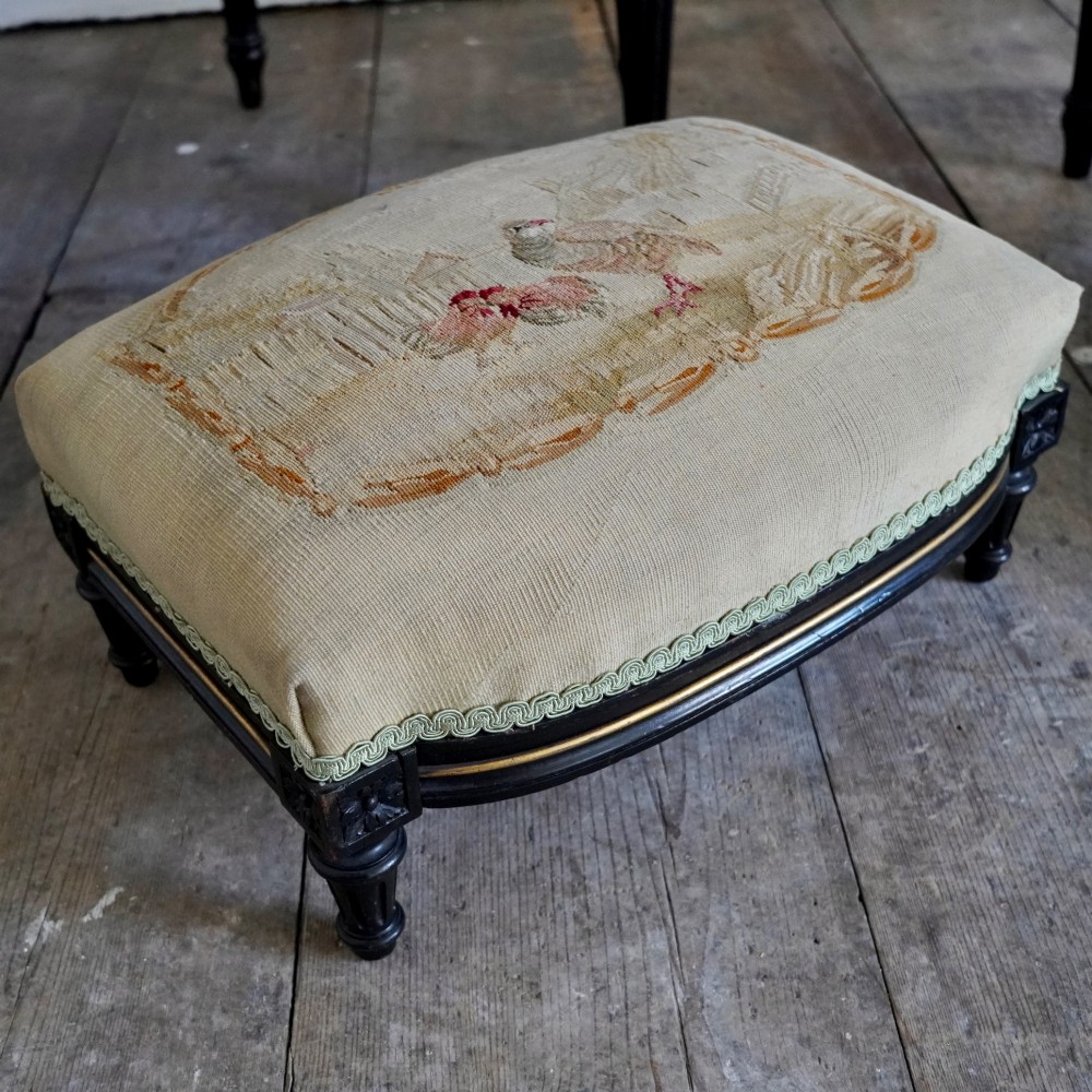 A pair of ebonised beech Louis XVI Revival salon armchairs featuring carved frames, fluted legs, padded armrests, and tapestry upholstery, accompanied by matching footstools. View VIII