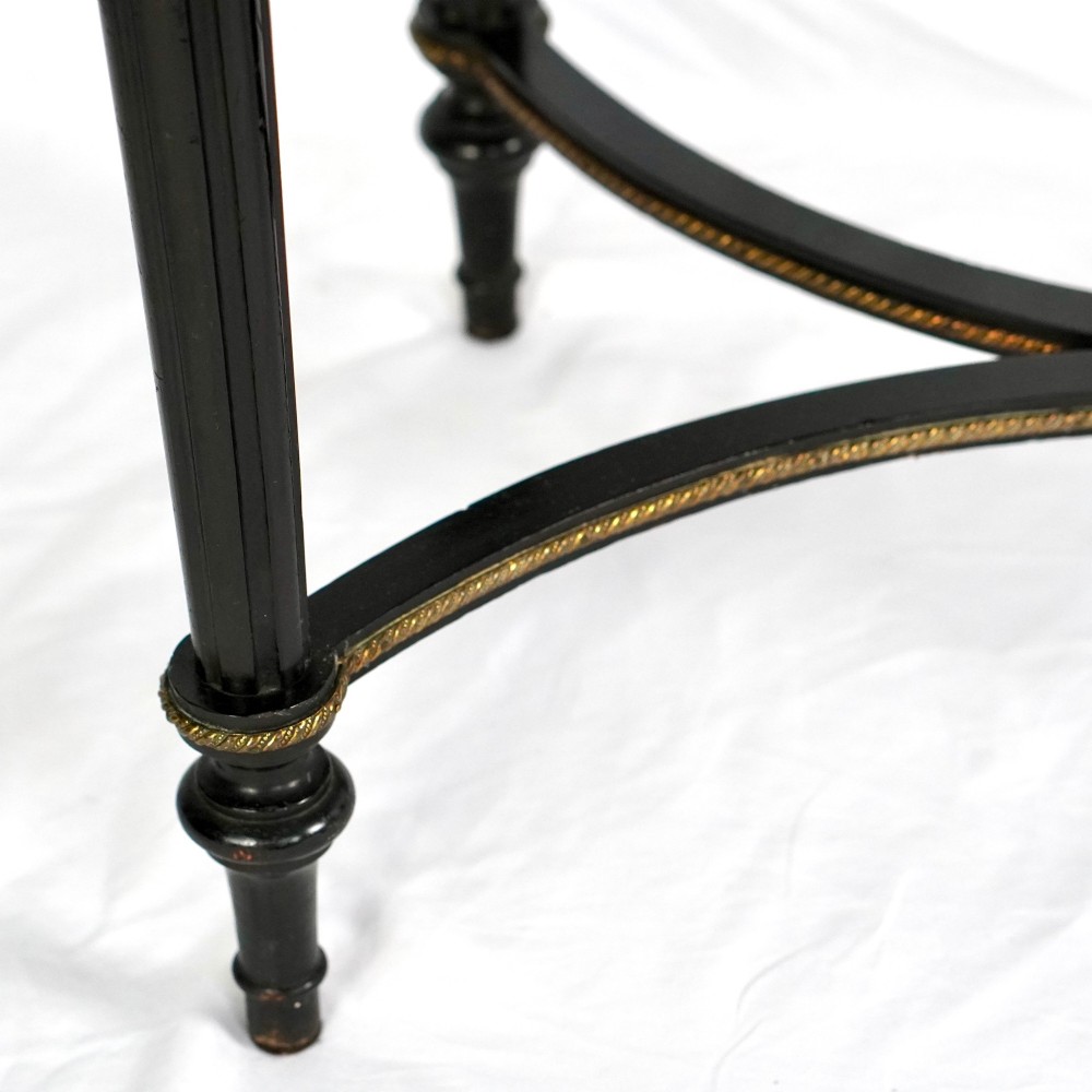 A French Napoleon III ebonised jardiniere stand featuring gilt highlights, inset painted porcelain plaques, a pierced brass gallery top, turned legs, and an arched lower stretcher. View VI