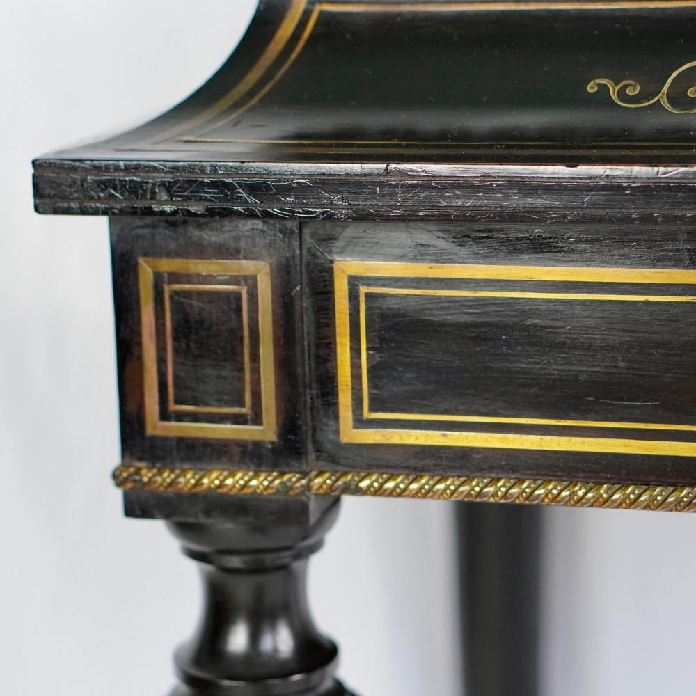 A French Napoleon III ebonised jardiniere stand featuring gilt highlights, inset painted porcelain plaques, a pierced brass gallery top, turned legs, and an arched lower stretcher. View XII