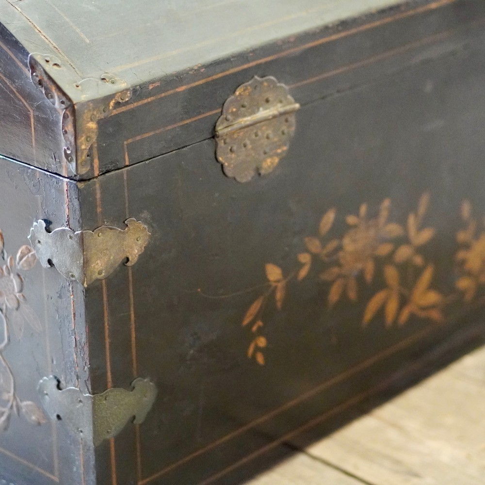 A 19th-century black lacquered domed storage trunk decorated with gilded chinoiserie landscape scenes and metal corner hardware. View X