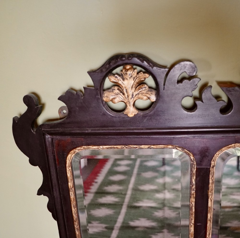 A dark mahogany triptych overmantel mirror with carved pierced fretwork, three mirror panels, and a gilded ho-ho bird cresting. View II
