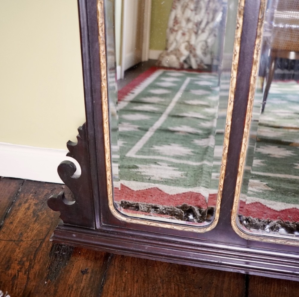 A dark mahogany triptych overmantel mirror with carved pierced fretwork, three mirror panels, and a gilded ho-ho bird cresting. View V