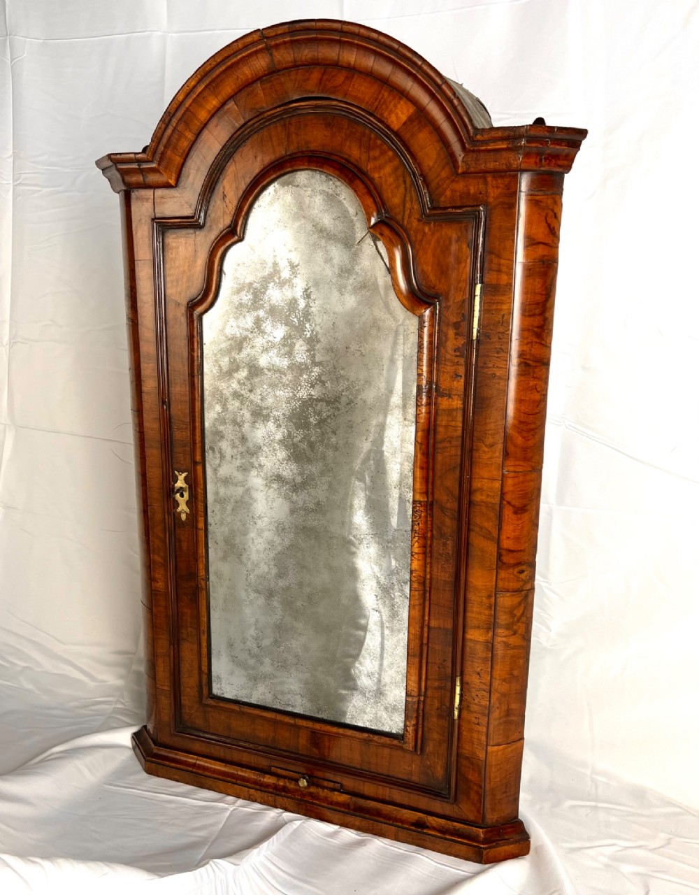 A Queen Anne walnut hanging corner cupboard featuring a double-moulded arched cornice, a mirrored door panel, and an integrated candle slide. View II