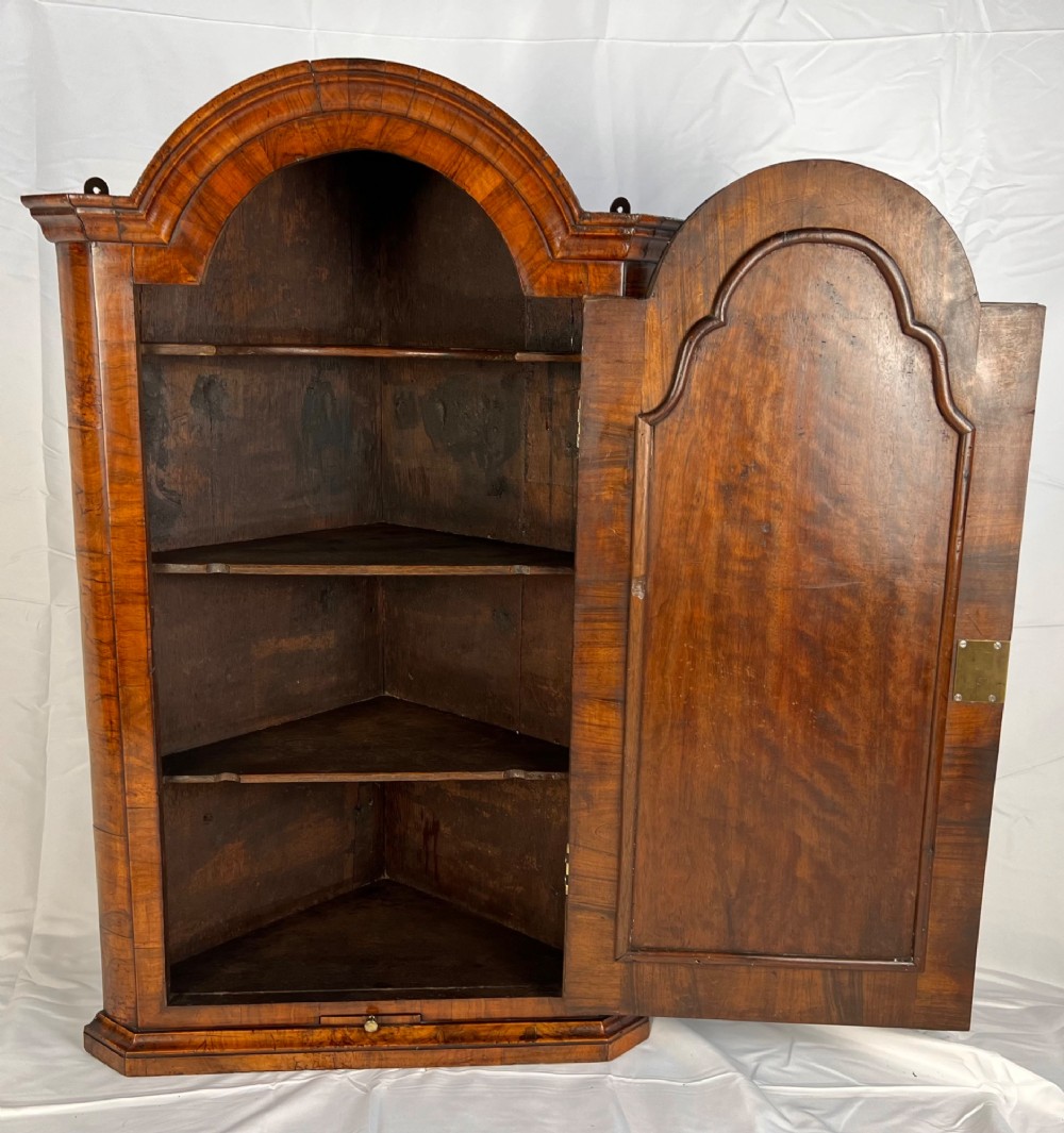 A Queen Anne walnut hanging corner cupboard featuring a double-moulded arched cornice, a mirrored door panel, and an integrated candle slide. View VI