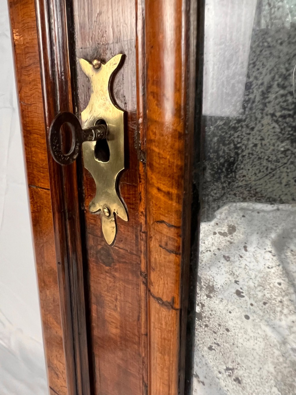 A Queen Anne walnut hanging corner cupboard featuring a double-moulded arched cornice, a mirrored door panel, and an integrated candle slide. View VIII
