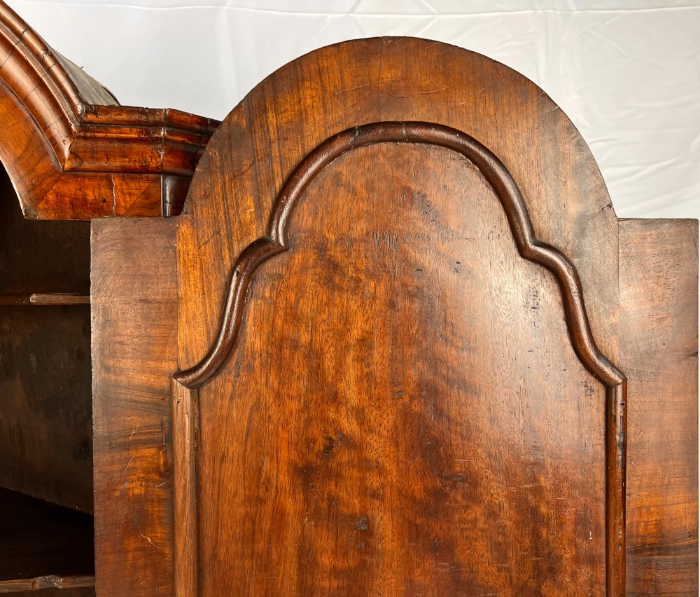 A Queen Anne walnut hanging corner cupboard featuring a double-moulded arched cornice, a mirrored door panel, and an integrated candle slide. View XII