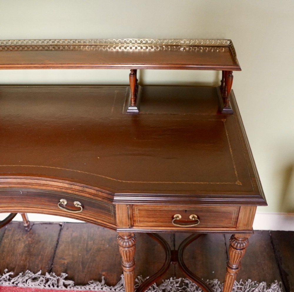 A Victorian rosewood writing desk featuring a brass gallery shelf, three drawers with brass handles, turned fluted legs, and curved stretchers. View III