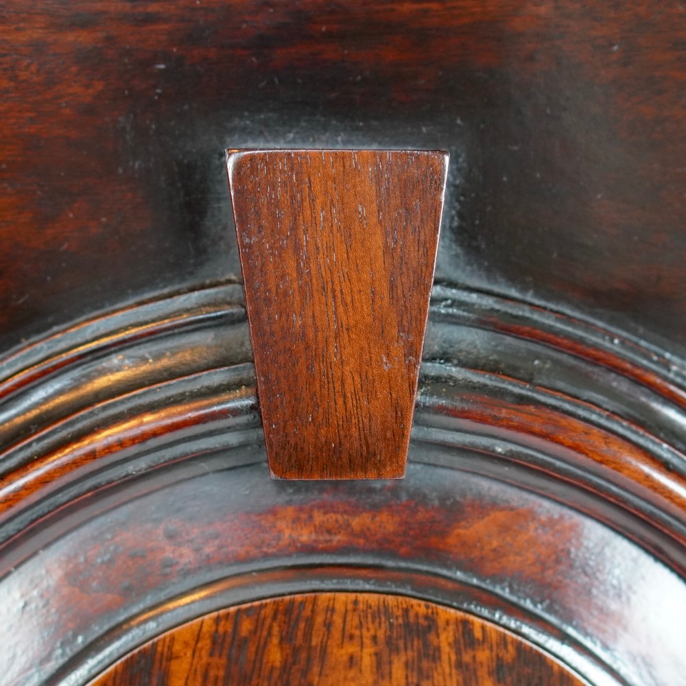 A Georgian mahogany hanging corner cupboard featuring an arched fielded panel door, brass H-hinges, key escutcheon, and a lower drawer. View VI