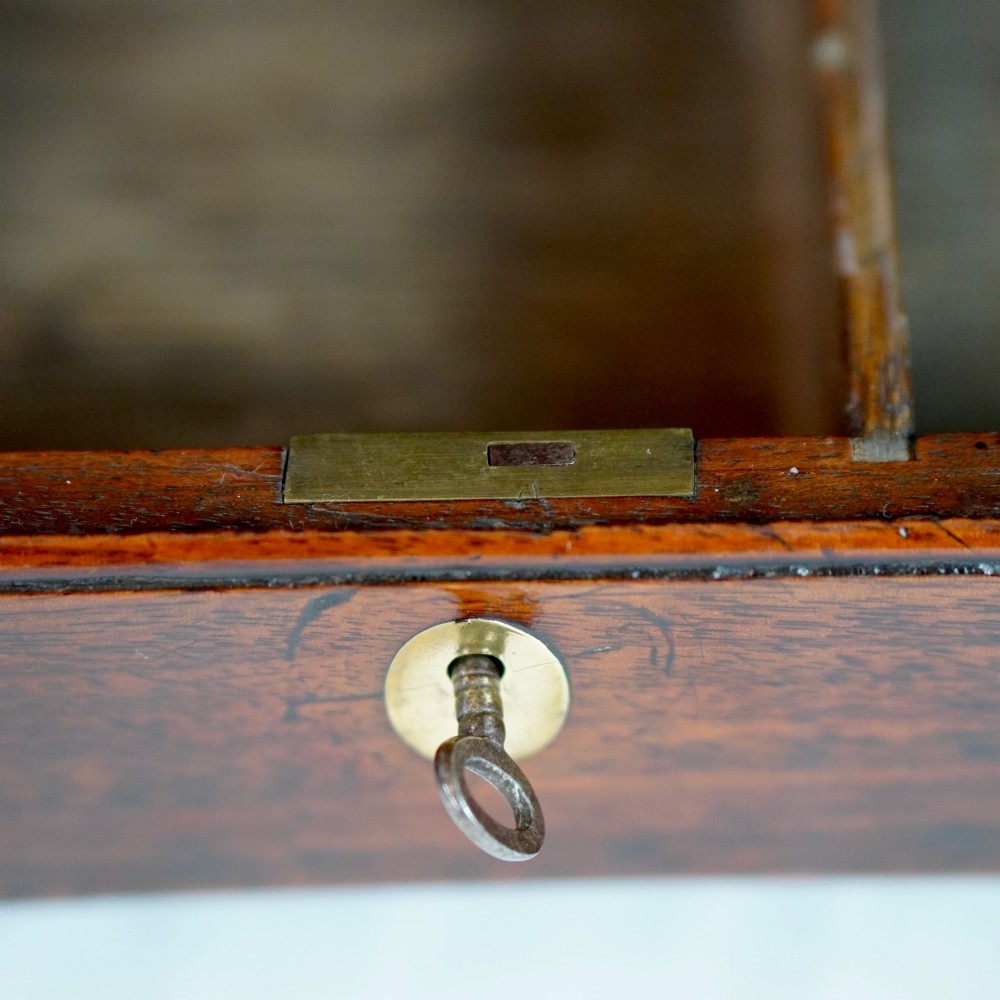 A Georgian mahogany hanging corner cupboard featuring an arched fielded panel door, brass H-hinges, key escutcheon, and a lower drawer. View XII
