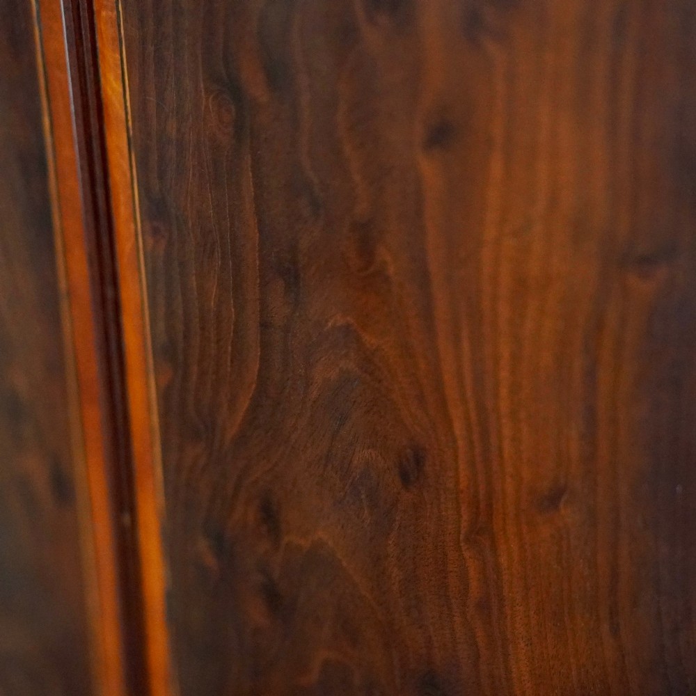 A George III bow front mahogany corner cabinet featuring polished plum pudding veneers, inlaid border stringing, and two curved doors. View IV